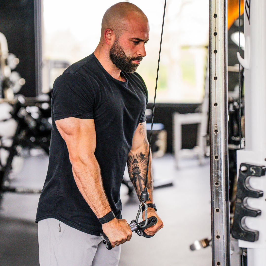 Lifter performing a tricep pushdown with the Uclips W Grip in a home gym