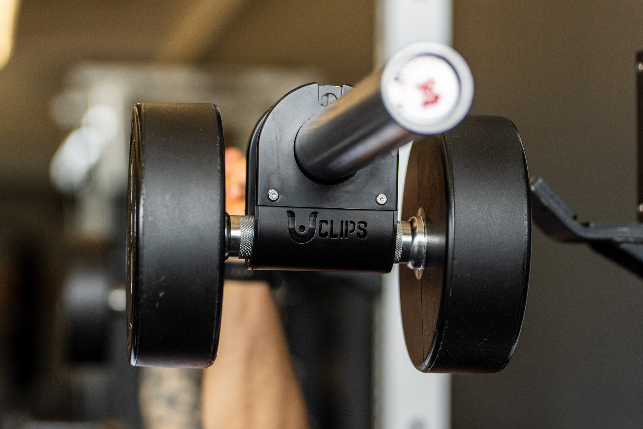A U Clip clamping a dumbbell onto the sleeve of a barbell to use it as bar weight